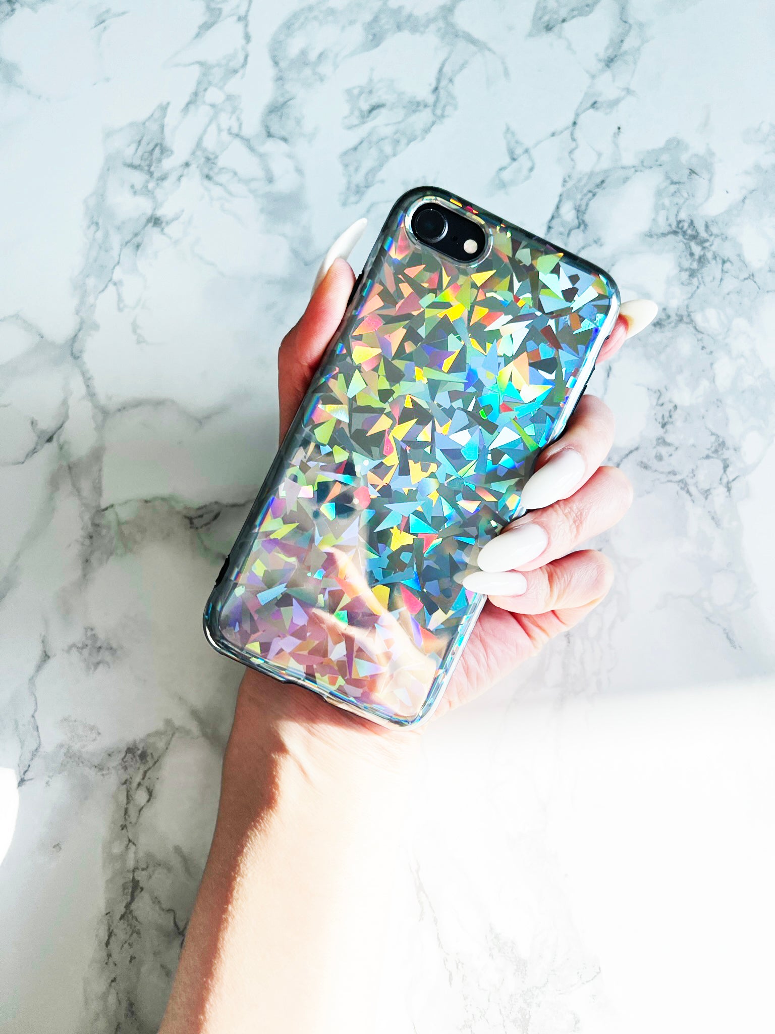 Holding Up KokoLoveCo Laser Focus Holographic iPhone Case with marble tabletop background