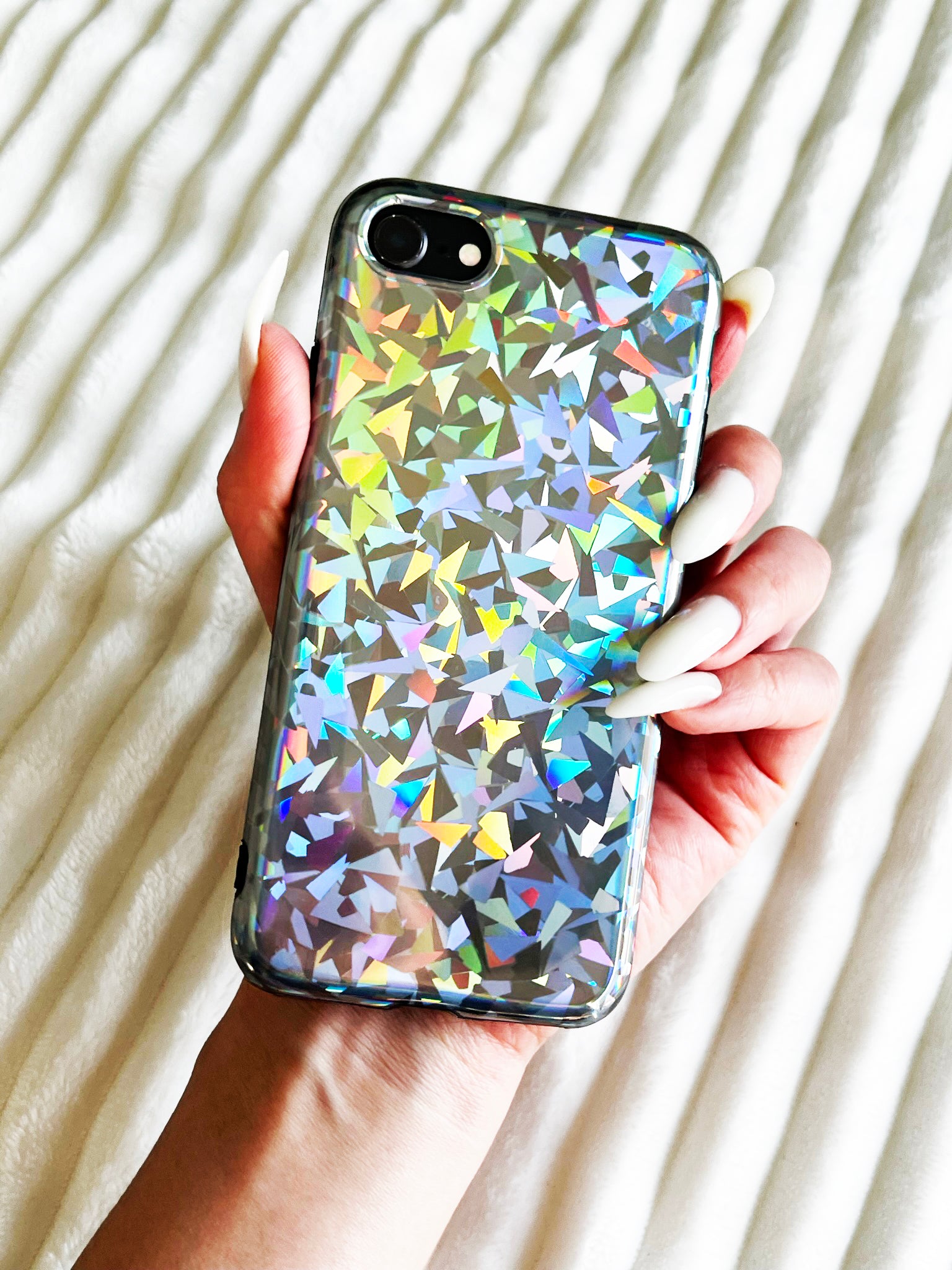 KokoLoveCo Laser Focus iPhone Case super shiny and colorful, on top of a white fluffy texture blanket