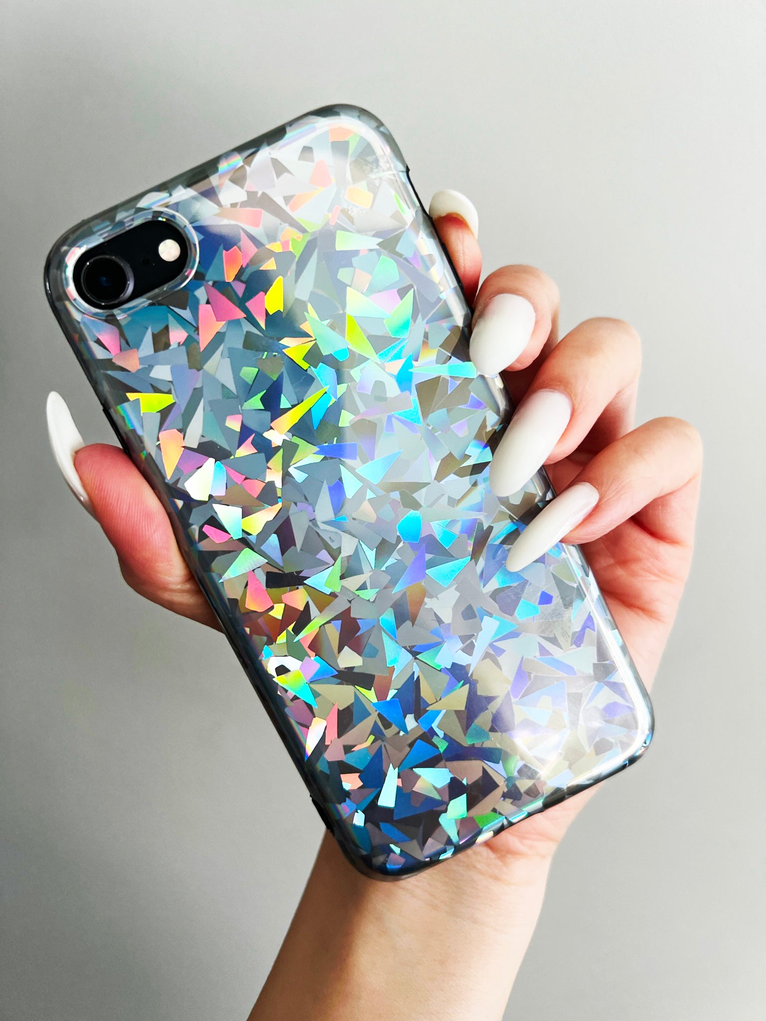 Colorful and super shiny holographic iphone case in front of a grey wall - Laser Focus by KokoLoveCo